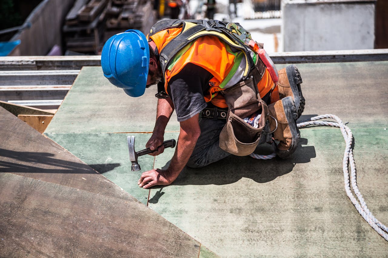 services-03 A skilled construction worker in protective gear hammering a rooftop panel.